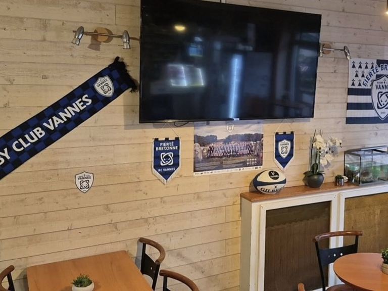 La salle du bar avec son grand écran, l'écharpe du Rugby Club Vannes et les fanions au mur