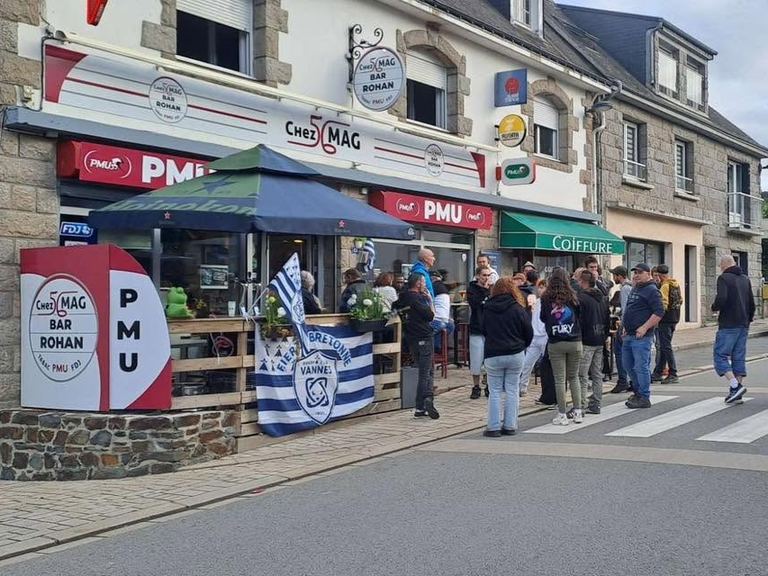 Des supporters rassemblés devant le bar, drapeau du RC Vannes à la main
