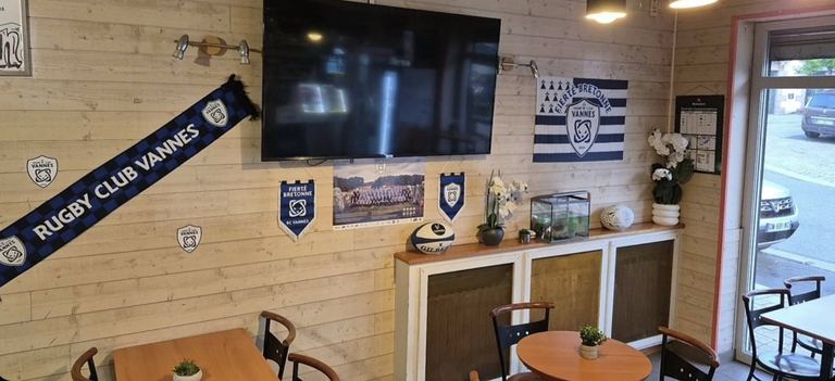 La salle du bar avec son grand écran, l'écharpe du Rugby Club Vannes et les fanions au mur