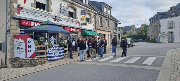 Des supporters rassemblés devant le bar, drapeau du RC Vannes à la main